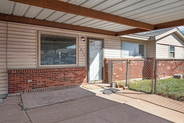 doorway to property with brick siding, fence, and a gate