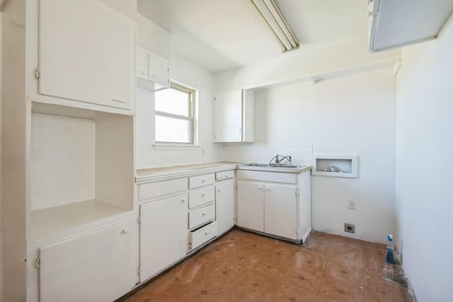 kitchen featuring a sink, white cabinets, and light countertops