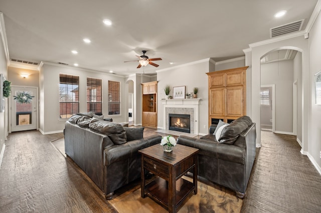 living room with baseboards, visible vents, arched walkways, and a tiled fireplace