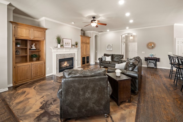 living room with baseboards, arched walkways, a tile fireplace, ceiling fan, and recessed lighting