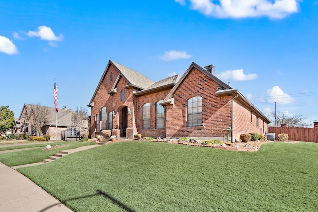 view of front of property featuring a front yard, brick siding, fence, and a chimney