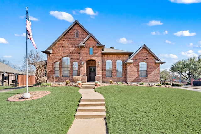 view of front of home featuring brick siding, fence, roof with shingles, a gate, and a front lawn