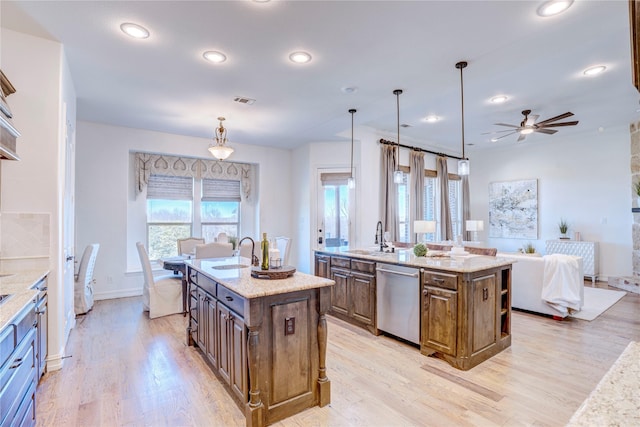 kitchen featuring dishwasher, a sink, a kitchen island with sink, and light wood-style floors