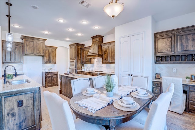 dining room featuring light wood-style floors, visible vents, arched walkways, and recessed lighting