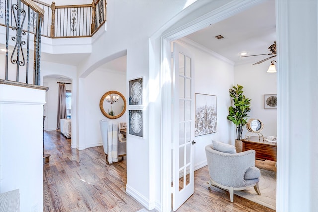 interior space with arched walkways, crown molding, visible vents, wood finished floors, and baseboards