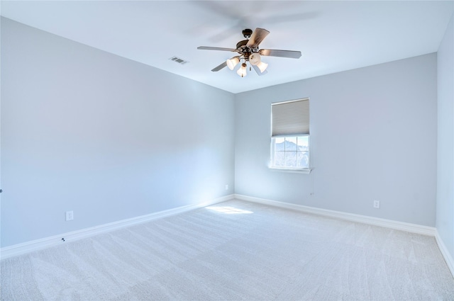 carpeted spare room with ceiling fan, visible vents, and baseboards