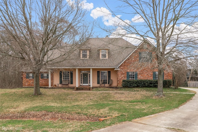 new england style home featuring covered porch, a front lawn, and stucco siding