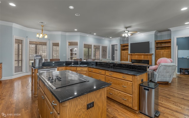 kitchen featuring visible vents, a large island, wood finished floors, black electric stovetop, and ceiling fan with notable chandelier