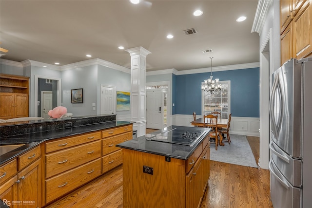 kitchen with visible vents, black electric stovetop, freestanding refrigerator, and brown cabinets