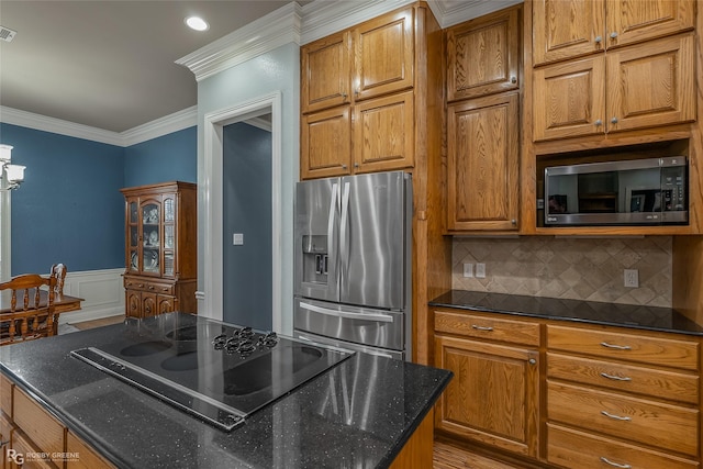 kitchen featuring stainless steel appliances, ornamental molding, brown cabinetry, and wainscoting