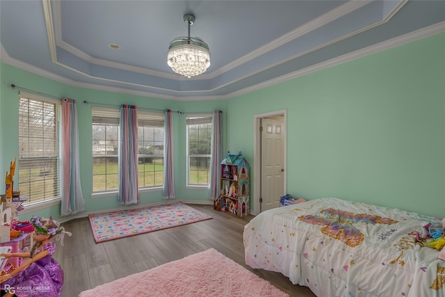 bedroom with an inviting chandelier, multiple windows, a raised ceiling, and wood finished floors