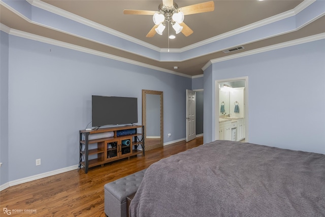 bedroom featuring wood finished floors, visible vents, baseboards, ornamental molding, and a tray ceiling