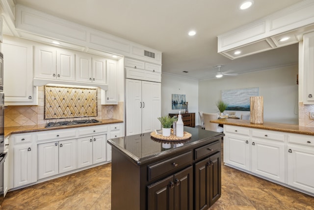 kitchen with stainless steel gas cooktop, crown molding, tasteful backsplash, white cabinetry, and ceiling fan