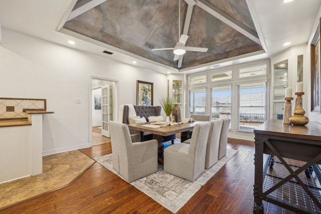 dining space with wood-type flooring, a raised ceiling, and visible vents