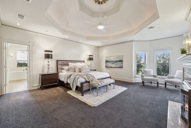 bedroom featuring dark colored carpet, multiple windows, a raised ceiling, and visible vents