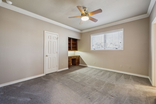 unfurnished bedroom with carpet, crown molding, built in desk, ceiling fan, and baseboards