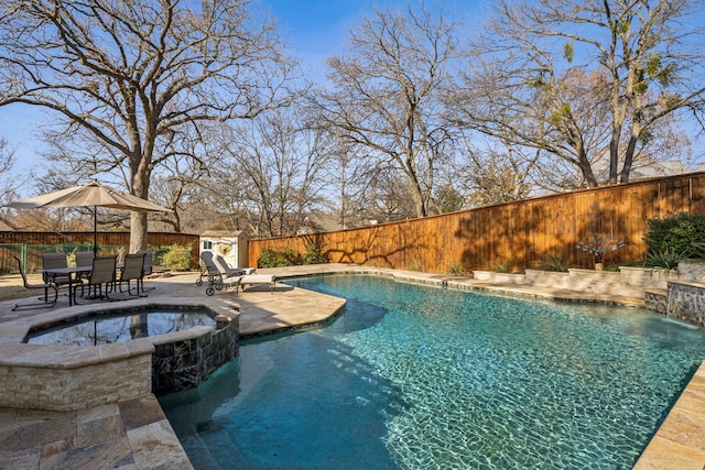 view of swimming pool with a fenced backyard, a pool with connected hot tub, an outdoor structure, and a patio