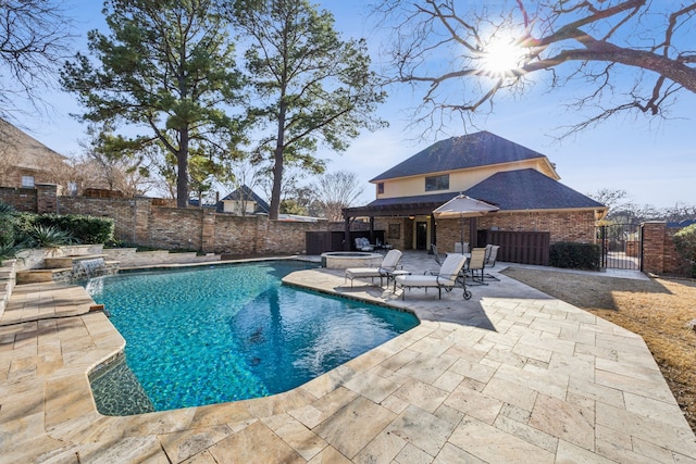 view of pool with a pool with connected hot tub, a patio area, a fenced backyard, and a gate