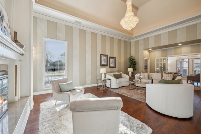 living room featuring a chandelier, wood finished floors, baseboards, wallpapered walls, and crown molding