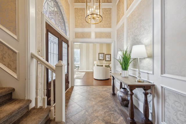 entrance foyer featuring a chandelier, a decorative wall, a high ceiling, french doors, and stairway