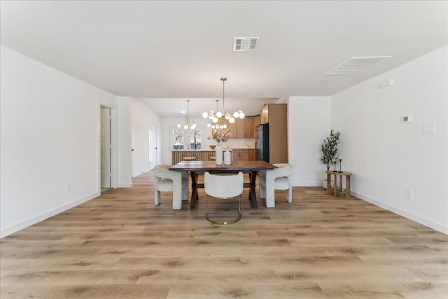 dining area featuring baseboards, light wood-style flooring, visible vents, and a notable chandelier