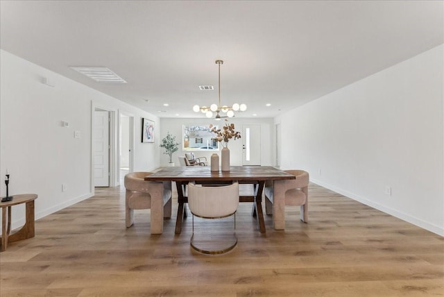 dining space with visible vents, light wood-style flooring, and an inviting chandelier