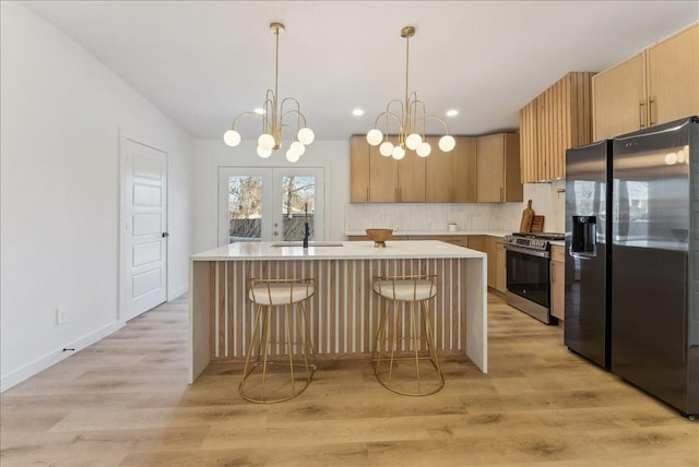 kitchen with fridge with ice dispenser, light countertops, light wood-style floors, stainless steel range with gas cooktop, and a sink