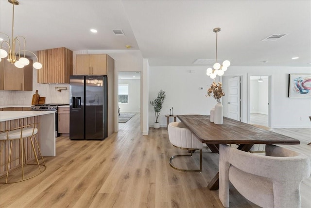 dining area featuring baseboards, light wood finished floors, visible vents, and an inviting chandelier