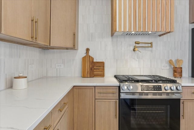 kitchen with light stone counters, gas range, and decorative backsplash