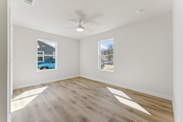 empty room with visible vents, ceiling fan, baseboards, and wood finished floors