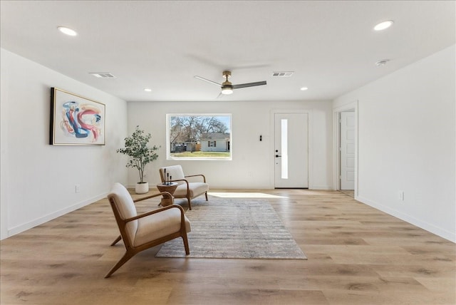 living area with light wood-type flooring, visible vents, and recessed lighting