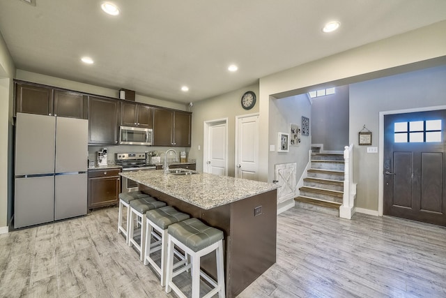 kitchen with light wood-style floors, appliances with stainless steel finishes, dark brown cabinets, and a sink