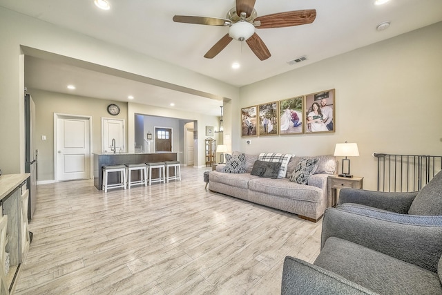 living area featuring light wood-style flooring, a ceiling fan, visible vents, and recessed lighting