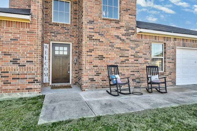 doorway to property featuring brick siding and roof with shingles