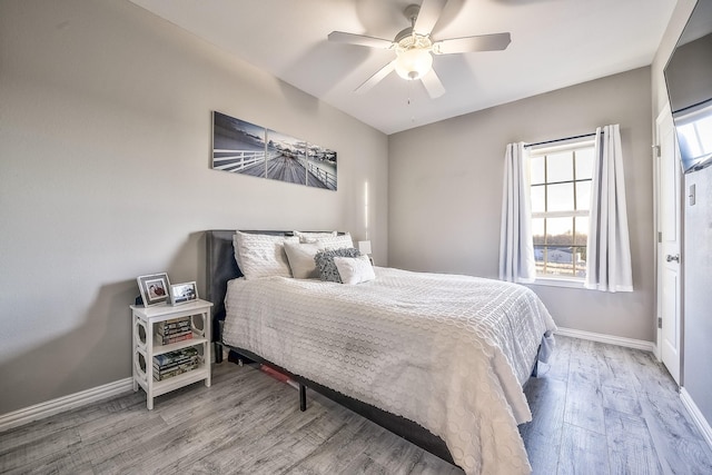 bedroom featuring a ceiling fan, baseboards, and wood finished floors