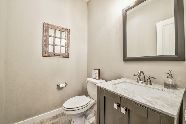 bathroom featuring baseboards, vanity, toilet, and wood finished floors