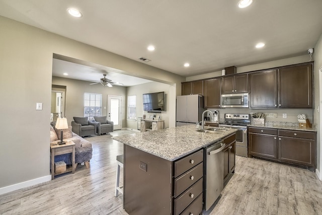 kitchen featuring appliances with stainless steel finishes, light wood-style floors, a sink, and dark brown cabinetry