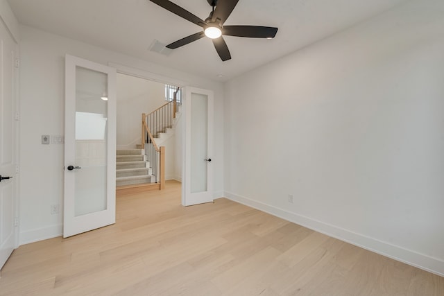 spare room with french doors, stairway, light wood-type flooring, and baseboards