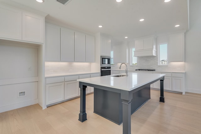 kitchen featuring stainless steel microwave, oven, light countertops, premium range hood, and a sink