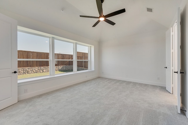 carpeted spare room featuring a ceiling fan, lofted ceiling, visible vents, and baseboards