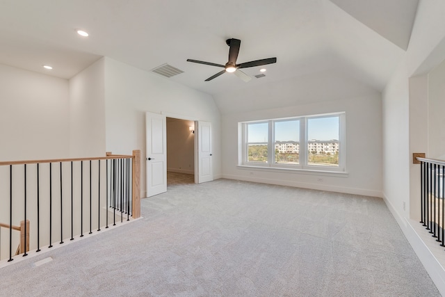 carpeted empty room featuring lofted ceiling, visible vents, baseboards, and recessed lighting