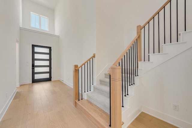 foyer with baseboards, stairway, a high ceiling, and wood finished floors