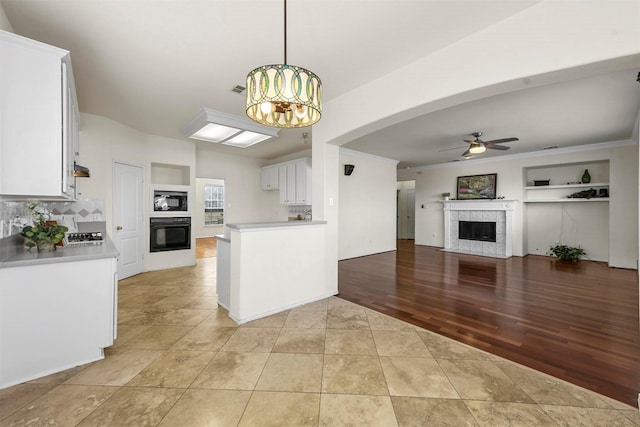 kitchen featuring black appliances, ceiling fan with notable chandelier, light countertops, and a tile fireplace