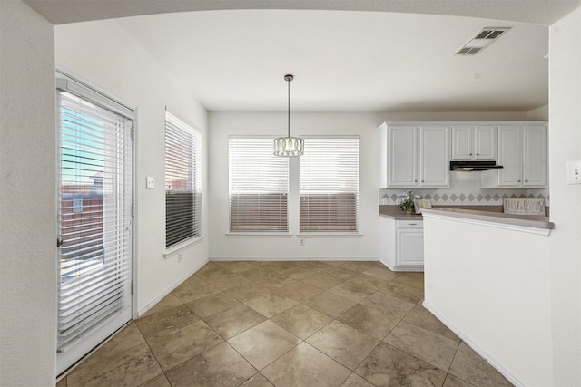 kitchen with decorative light fixtures, visible vents, backsplash, white cabinets, and under cabinet range hood