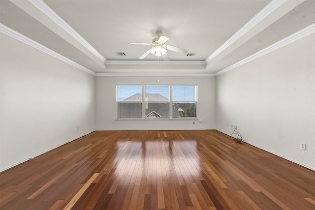 empty room with a tray ceiling, visible vents, and hardwood / wood-style floors