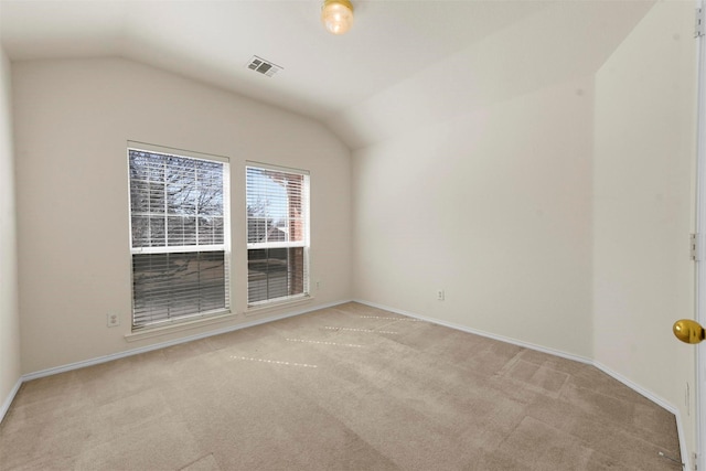 spare room featuring lofted ceiling, baseboards, visible vents, and light colored carpet