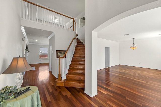 stairs with ornamental molding, arched walkways, visible vents, and hardwood / wood-style floors