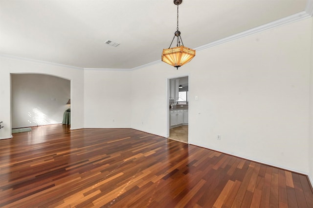 spare room featuring arched walkways, light wood finished floors, visible vents, and crown molding