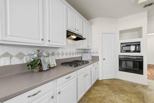 kitchen with under cabinet range hood, visible vents, white cabinetry, backsplash, and black appliances