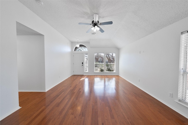 unfurnished living room featuring baseboards, ceiling fan, wood finished floors, vaulted ceiling, and a textured ceiling